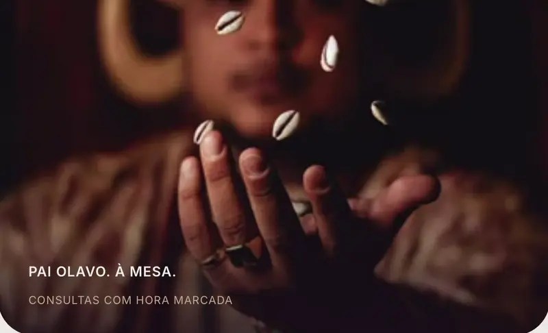 Pai Olavo durante uma leitura com búzios, com a mão em primeiro plano